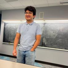 Rodrigo Gonzalez Hernandez A man in a blue shirt stands in front of a blackboard.