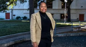 Kennedy Simon stands in front of a UT-Austin campus building with her hand on one hip.