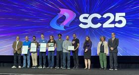 Eleven people stand onstage at SC25 holding certificates.