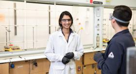 Graduate researcher talks to colleague in lab