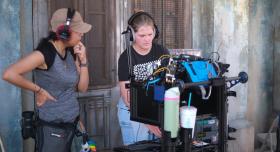 Two students operate equipment on a film set.