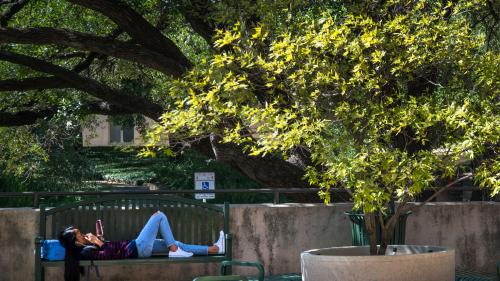 student relaxing outside on bench