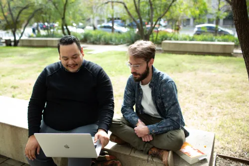 two students outside looking at computer
