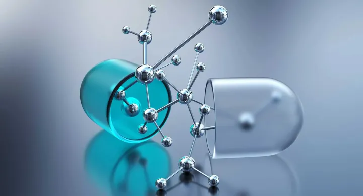 Against a clear background, a translucent pill, half turquoise and half clear, is split open to reveal silver molecules branching out of it.