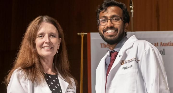 A man and a woman in white doctor's coats stand in front of a whiteboard.