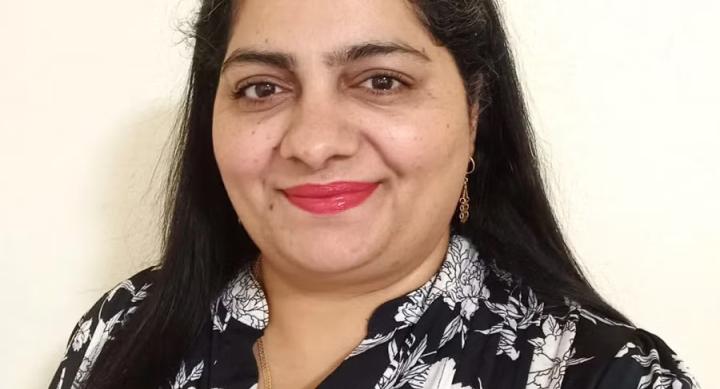 A person wears a black and white floral shirt and stands in front of a white background.