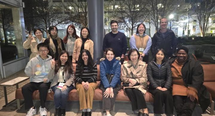 A group of people takes a group photo outdoors at night.