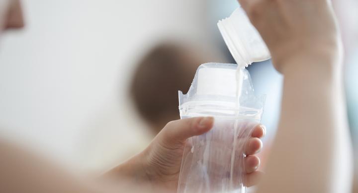 A person pours milk into a plastic bag.