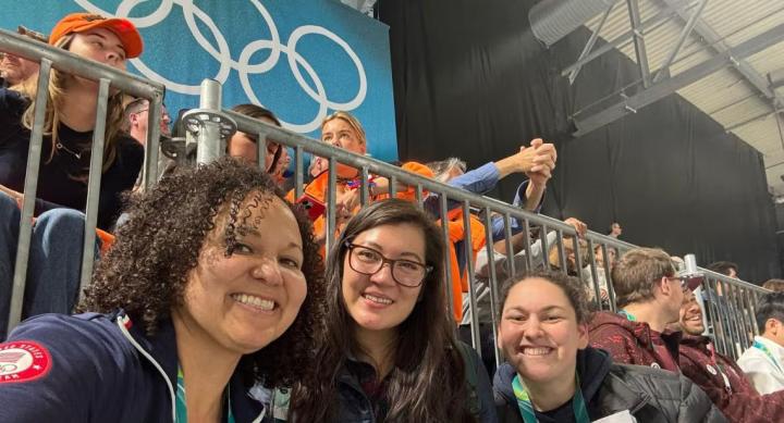 Three people pose for a photo in the crowd of an Olympic sporting event.