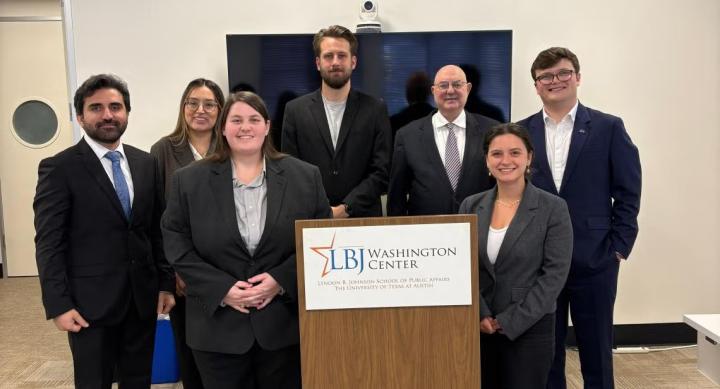 A group of people in formalwear stand around a podium.