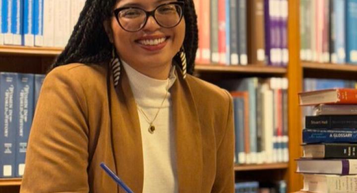 A person sits at a desk in a library wearing professional attire.