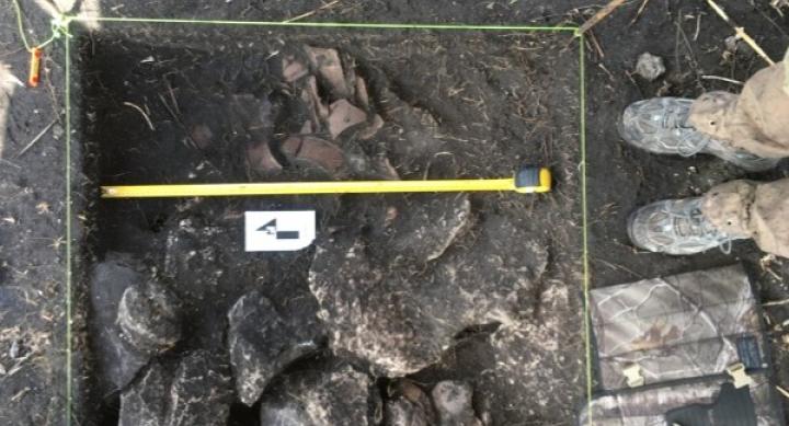 A measuring tape is laid over some rocks on a dig site.