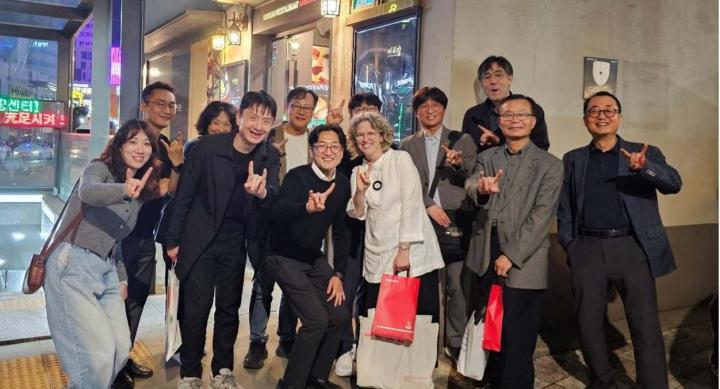 A group of professors and students make a Hook 'em hand sign on the streets of Seoul.