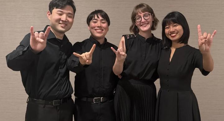 A group of students make the Hook 'em hand sign.