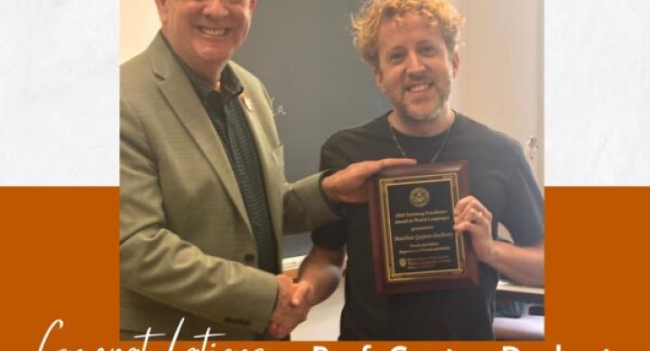A professor and a student shake hands while holding an awards certificate.
