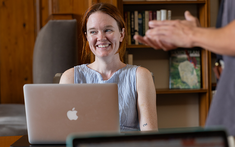 student smiling while sitting in front of laptop