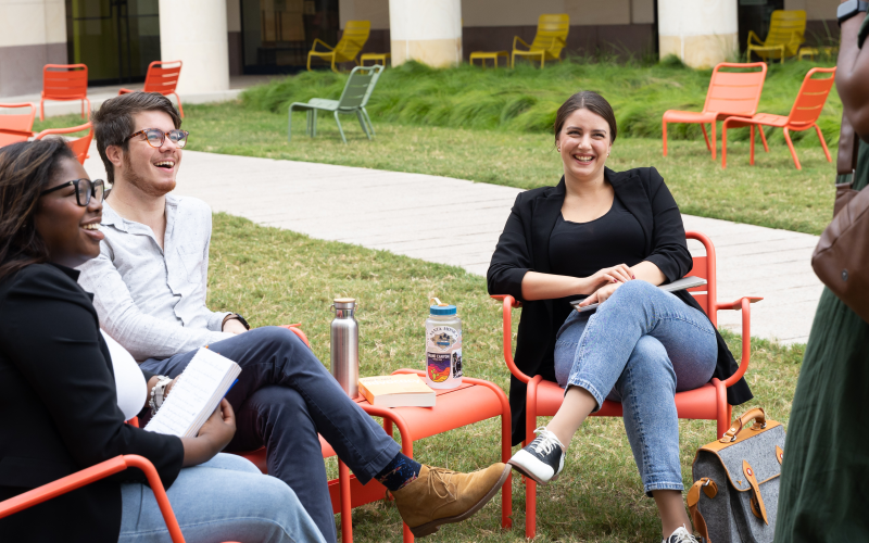 three graduate students sitting and talking to a staff member